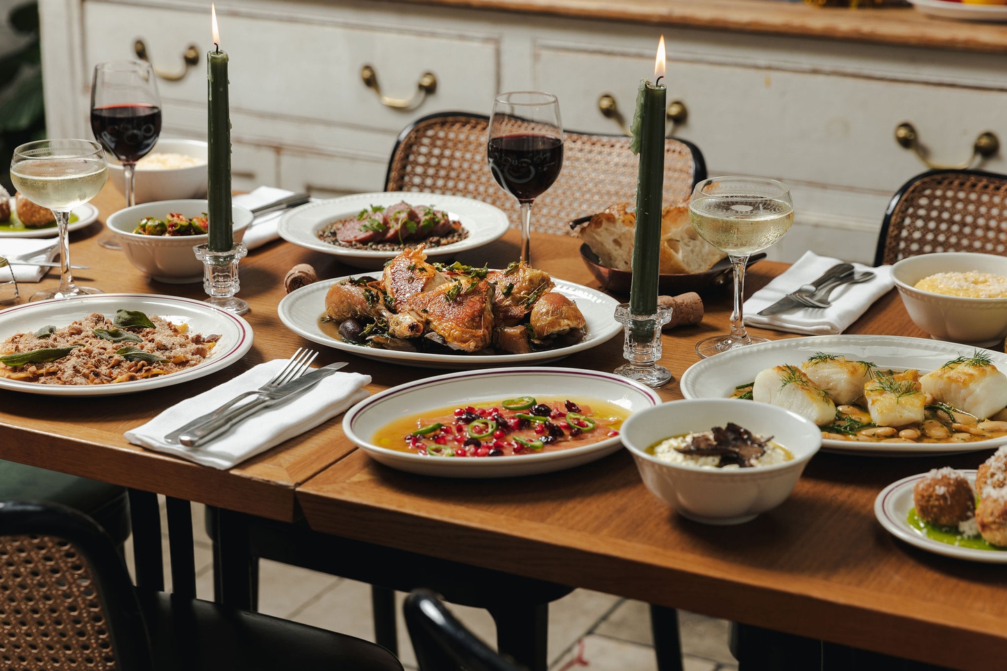 Table filled with an Italian feast at Mortimer House Kitchen, featuring roasted chicken, fresh pasta, seafood, vibrant salads, and wine.