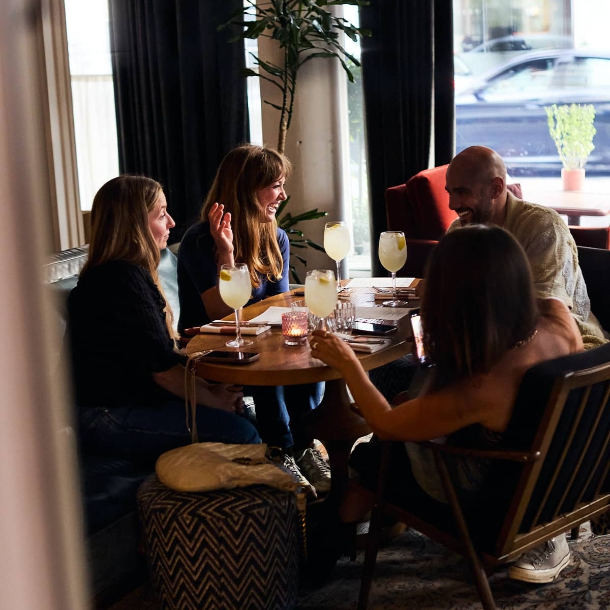 Group of friends enjoying drinks and conversation in the cozy lounge area of Mortimer House Kitchen.