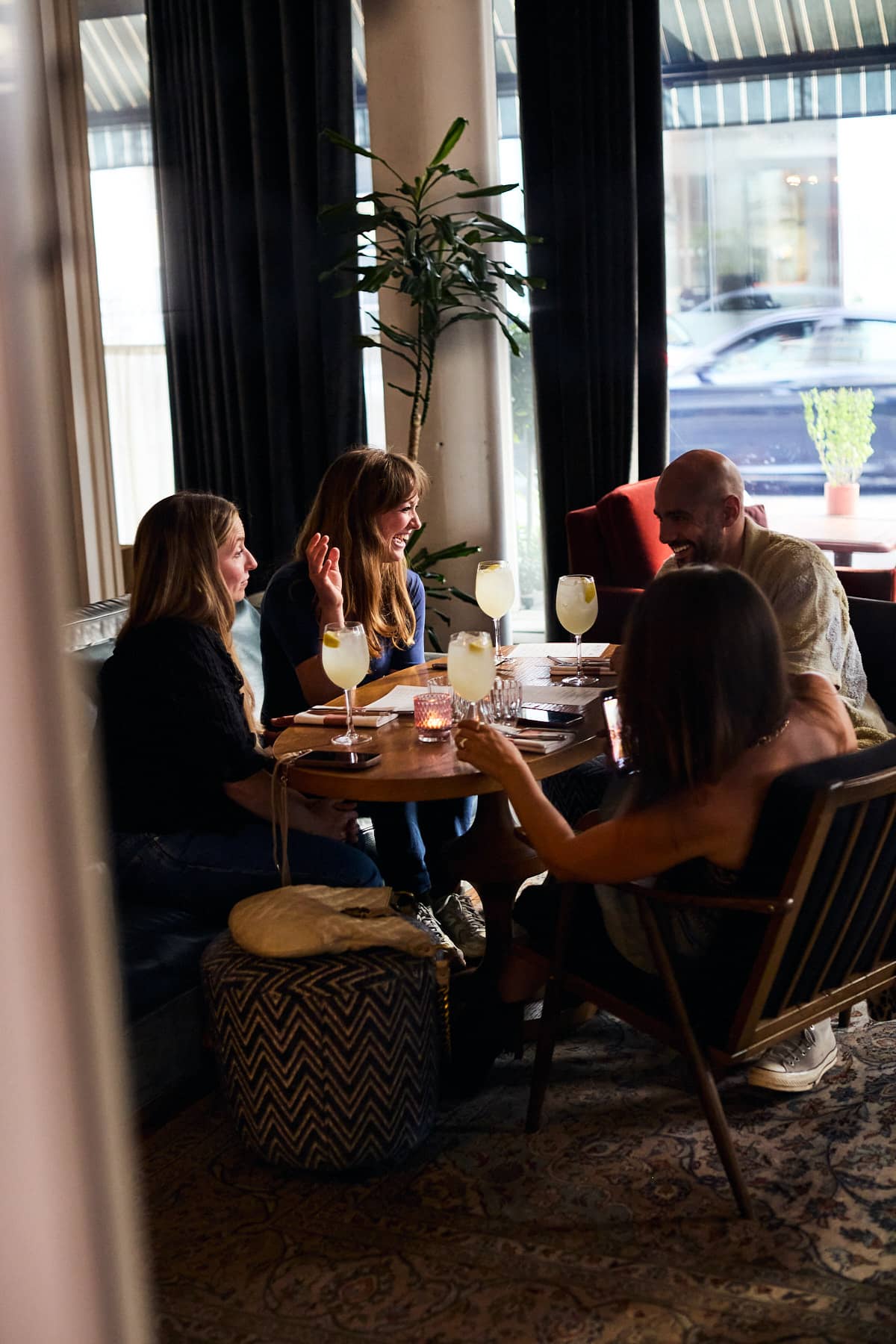 Group of friends enjoying drinks and conversation in the cozy lounge area of Mortimer House Kitchen.