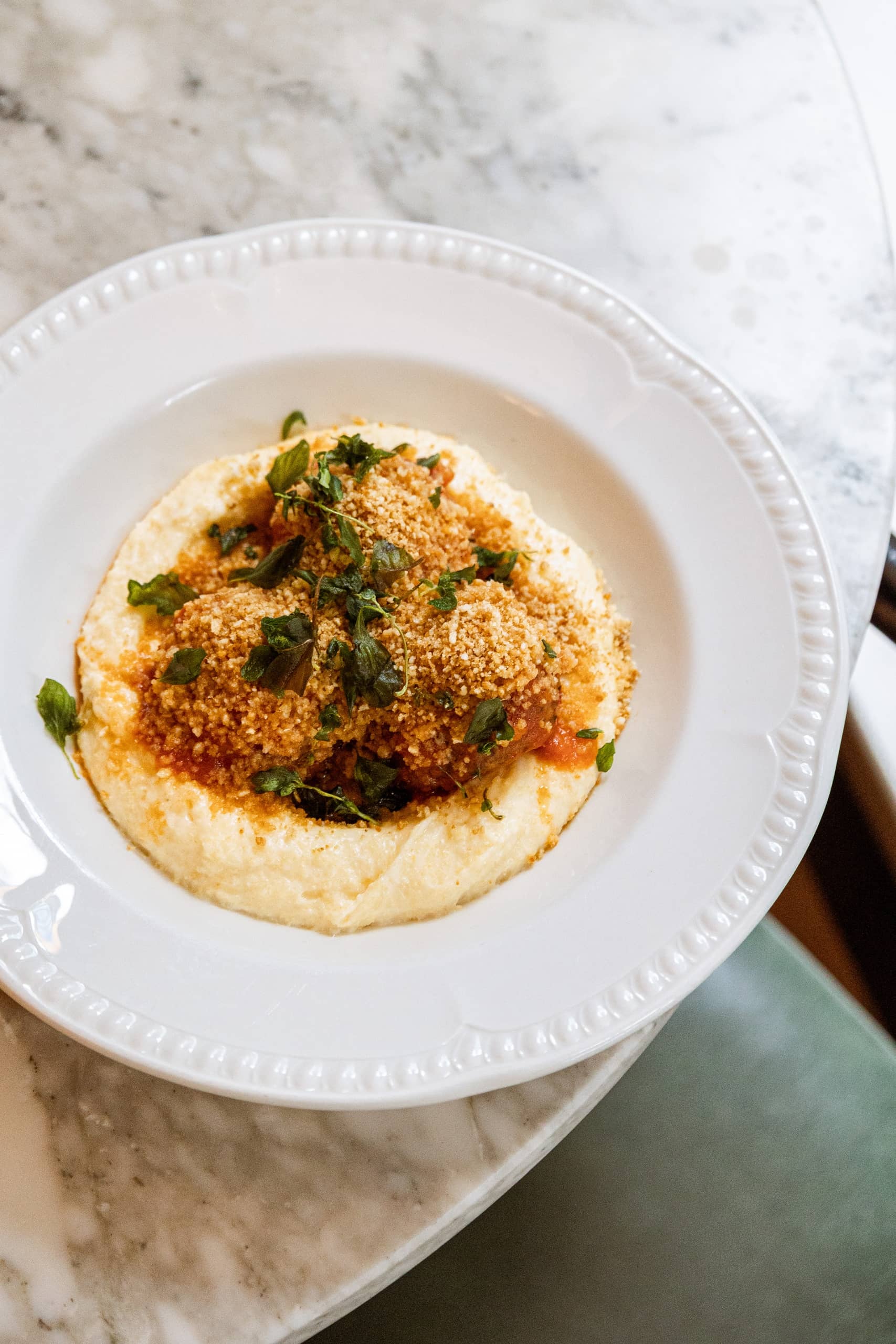 Velvety polenta topped with tomato ragu, golden breadcrumbs, and fresh herbs served at Mortimer House Kitchen.