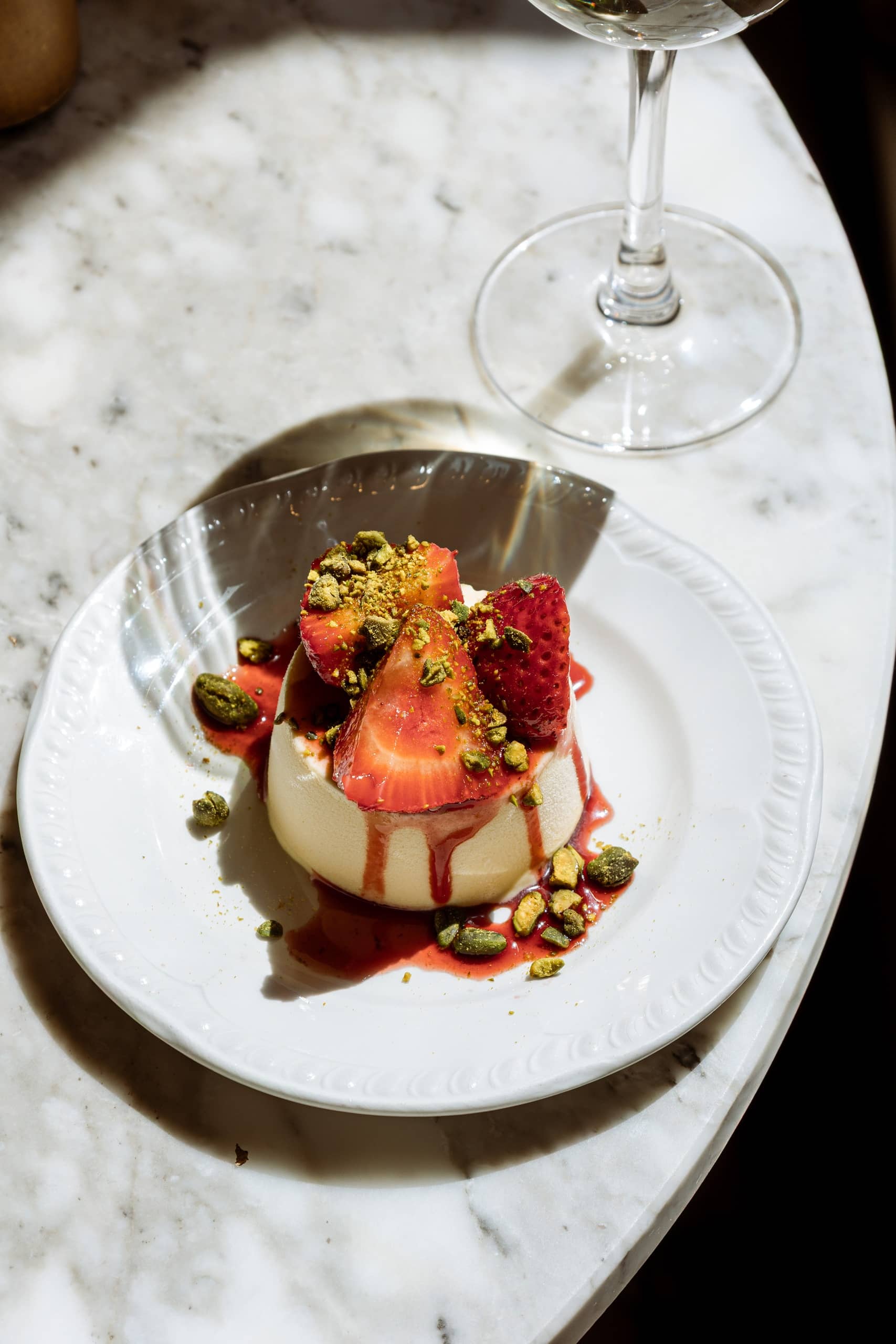 Elegant panna cotta topped with fresh strawberries, pistachios, and berry coulis served at Mortimer House Kitchen.