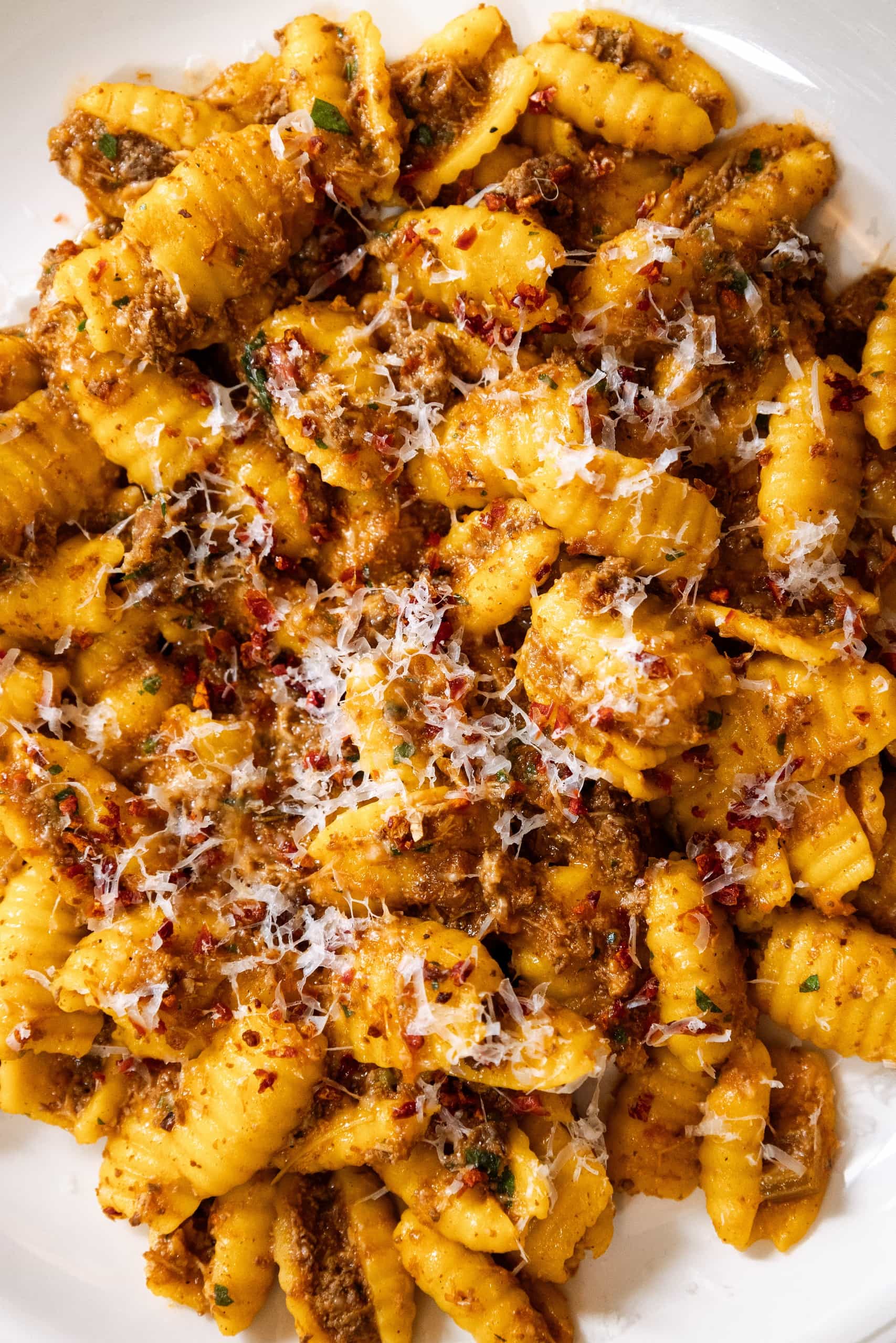 Close-up of handmade gnocchetti pasta with rich meat ragu, garnished with grated parmesan, chili flakes, and fresh herbs at Mortimer House Kitchen.